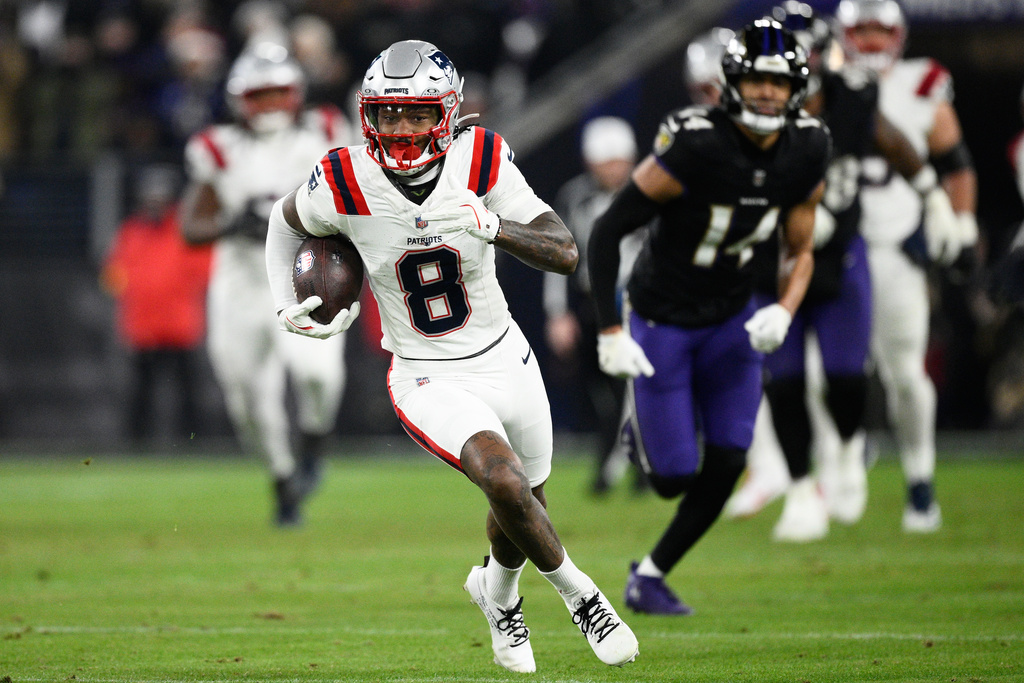 New England Patriots wide receiver Stefon Diggs (8) runs in front of Baltimore Ravens safety Kyle Hamilton (14) during the first half of an NFL football game, Sunday, Dec. 21, 2025, in Baltimore. (AP Photo/Nick Wass)