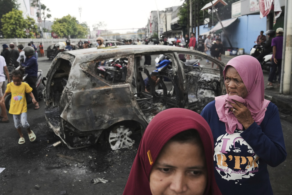 People inspect the wreckages of cars burned in violent protests against lawmakers' allowance and alleged police brutality after a delivery rider was run over by a police armored vehicle during clashes between riot police and students protesters, in Jakarta, Indonesia, Saturday, Aug. 30, 2025. (AP Photo/Dita Alangkara)