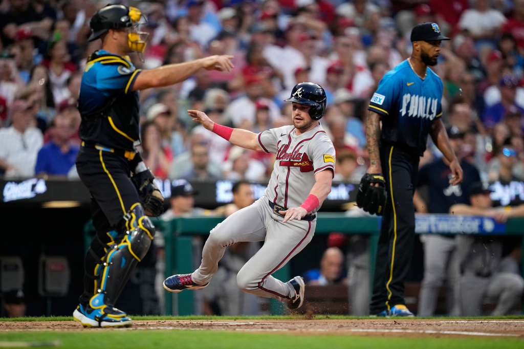 Atlanta Braves' Lane Thomas, center, scores past Philadelphia Phillies catcher J.T. Realmuto, left, and pitcher Cristopher S&aacute;nchez on a single by Austin Riley during the second inning of a baseball game Friday, Sept. 4, 2026, in Philadelphia. (AP Photo/Matt Slocum)