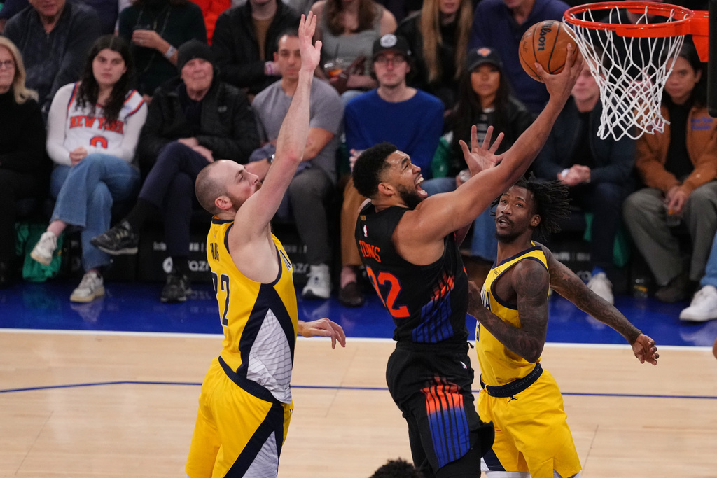 New York Knicks' Karl-Anthony Towns (32) drives past Indiana Pacers' Jay Huff (32) during the second half of an NBA basketball game Tuesday, March 17, 2026, in New York. (AP Photo/Frank Franklin II)