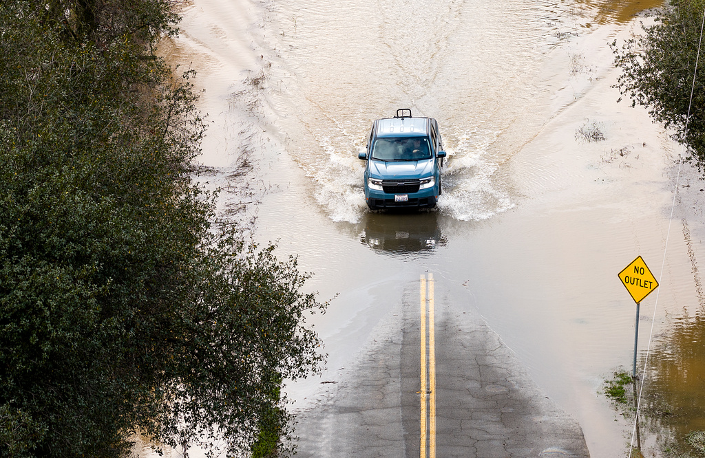 A car drives down a flooded road following heavy rains, on Monday, Dec. 22, 2025, in Redding, Calif. (AP Photo/Noah Berger)