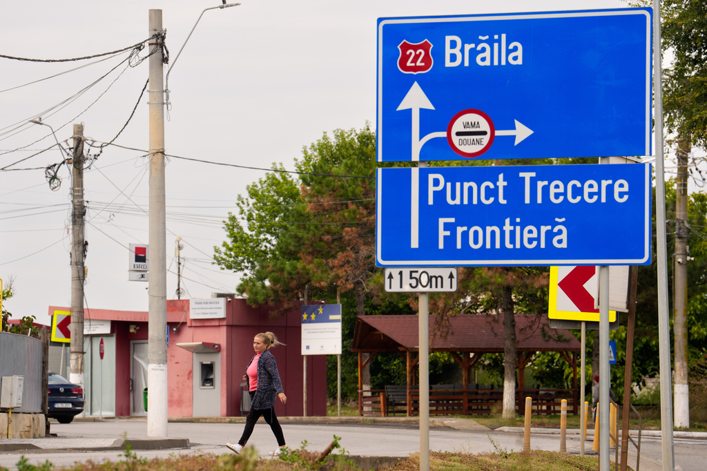 A woman walks by a traffic sign showing the way to a border crossing point in Isaccea, a town on the Romanian-Ukrainian border, Romania, Monday, Sept. 14, 2026. (AP Photo/Vadim Ghirda)