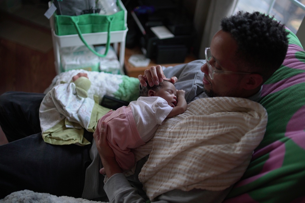 First-time dad JaKobi Burton holds his newborn daughter, Phoenix RyZen Reign Burton, at their home in Indianapolis, Nov. 13, 2025. (AP Photo/Obed Lamy)