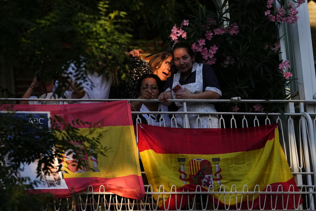 People catch a glimpse from their homes of Pope Leo XIV arriving at Plaza de Lima in Madrid, Saturday, June 6, 2026, for a prayer vigil with young people on the first day of a seven-day apostolic journey to mainland Spain and the Canary Islands. (AP Photo/Alessandra Tarantino)