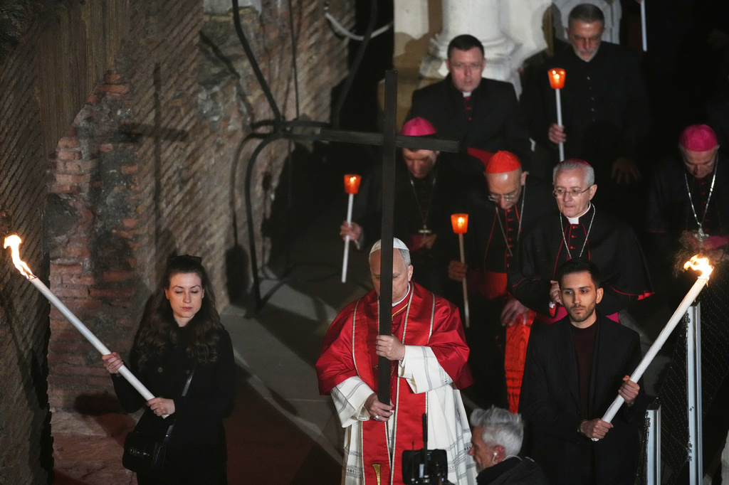 Pope Leo XIV carries a lightweight, 1.5-meter (5-foot) wooden cross during the Via Crucis, the torchlit Good Friday Stations of the Cross procession at the Colosseum in Rome, Friday, April 3, 2026, which symbolically retraces Jesus Christ's steps to his crucifixion on Calvary in Jerusalem. (AP Photo/Alessandra Tarantino)