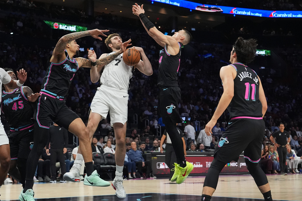 San Antonio Spurs center Luke Kornet (7) fights for control of the ball against Miami Heat center Kel'el Ware, left, and guard Tyler Herro, second from right, during the first half of an NBA basketball game, Monday, March 23, 2026, in Miami. (AP Photo/Lynne Sladky)