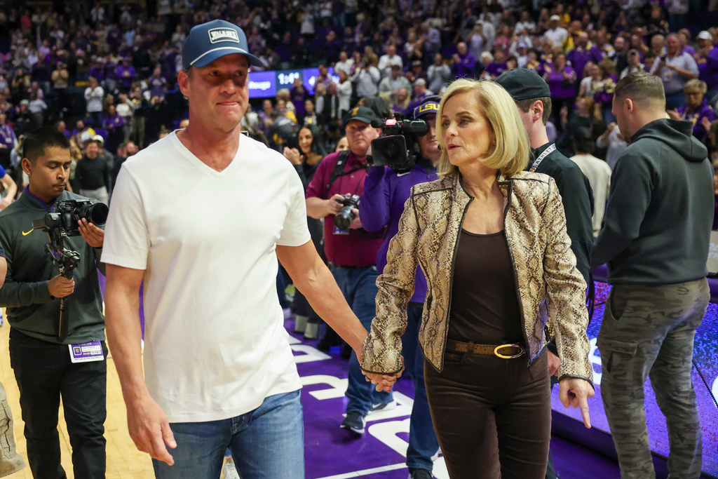 LSU head coach Kim Mulkey, right, brings head football coach Lane Kiffin out onto the court in the first half of an NCAA college basketball game against Kentucky in Baton Rouge, La., Thursday, Jan. 1, 2026. (AP Photo/Peter Forest)