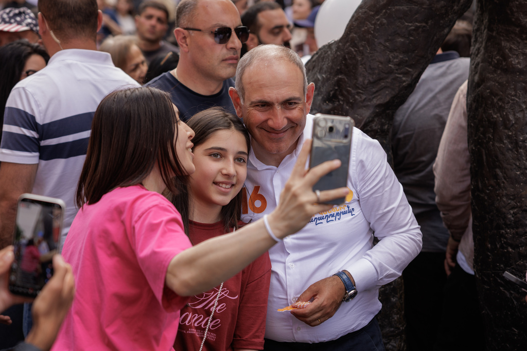 Armenian Prime Minister Nikol Pashinyan poses for a selfie photo with a supporter as he walks on Northern Avenue in Yerevan, Armenia, Monday, June 1, 2026, during public celebrations marking International Children's Day. (AP Photo/Anthony Pizzoferrato)