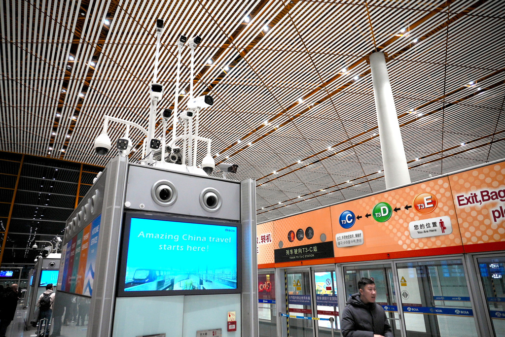 Surveillance cameras above a screen reading "Amazing China travel starts here!" monitor passengers at an airport in Beijing, China, Saturday, Dec. 21, 2024. (AP Photo/Dake Kang)