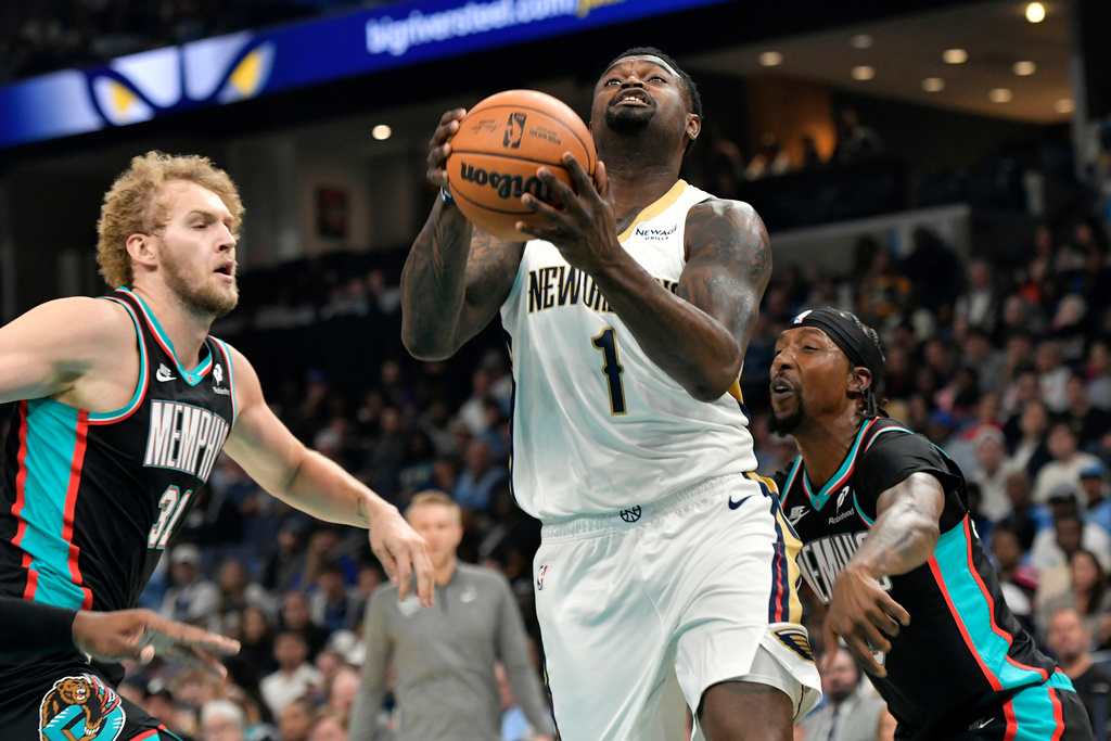 New Orleans Pelicans forward Zion Williamson (1) drives to the basket between Memphis Grizzlies center Jock Landale (31) and guard Kentavious Caldwell-Pope in the first half of an NBA basketball game Wednesday, Oct. 22, 2025, in Memphis, Tenn. (AP Photo/Brandon Dill)