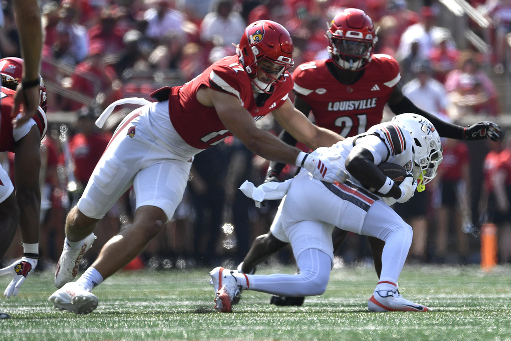 CORRECTS ID TO BOWLING GREEN RUNNING BACK KADEEM ROBERTS (0) , NOT BOWLING GREEN SAFETY KAL-EL PASCAL (0) - Louisville linebacker Kalib Perry (12) grabs Bowling Green running back Kadeem Roberts (0) during the first half of an NCAA college football game in Louisville, Ky., Saturday, Sept. 20, 2025. (AP Photo/Timothy D. Easley)