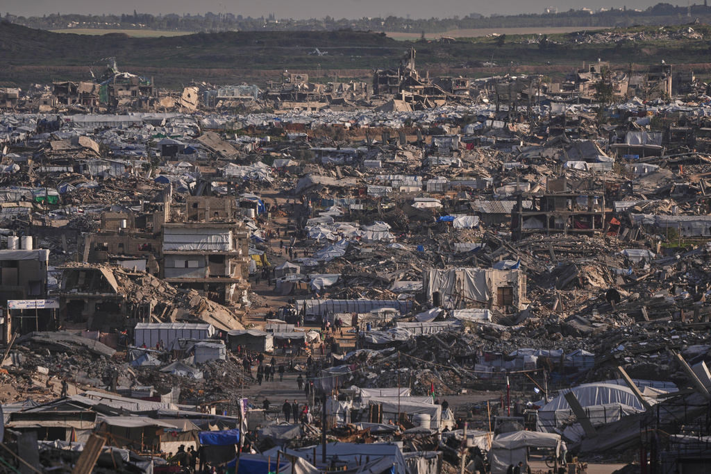 Makeshift tents shelter displaced Palestinians stand among buildings destroyed by Israeli air and ground operations in Gaza City Thursday, Jan. 15, 2026. (AP Photo/Jehad Alshrafi)