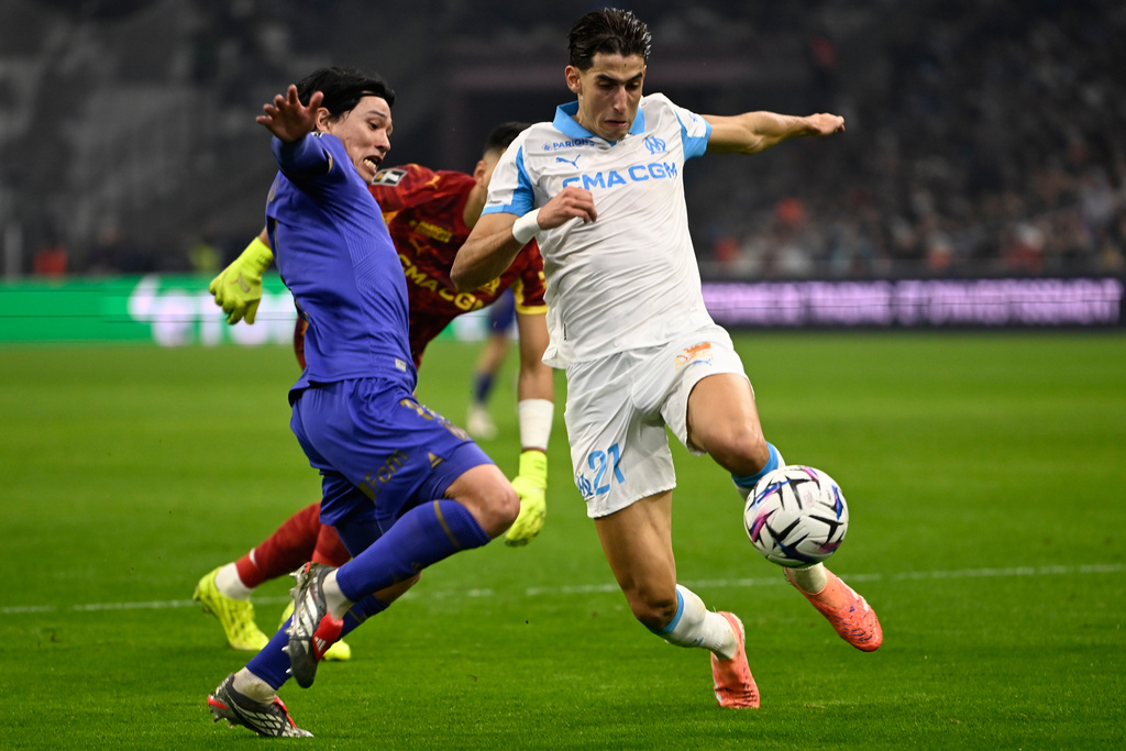 Marseille's Nayef Aguerd, right, challenges with Monaco's Takumi Minamino during the French League One soccer match between Marseille and Monaco in Marseille, France, Sunday, Dec. 14, 2025. (AP Photo/Philippe Magoni)