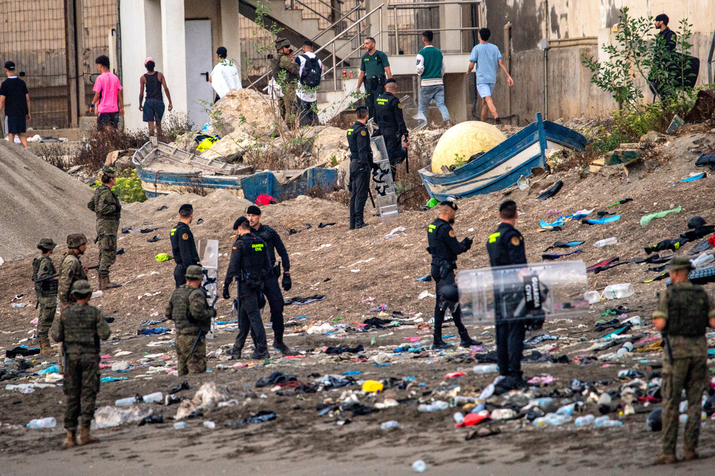 Spanish army soldiers and Guardia Civil officers stand guard as migrants return to Morocco from the Spanish enclave of Ceuta, Saturday, Aug. 1, 2026. (AP Photo/Antonio Sempere)