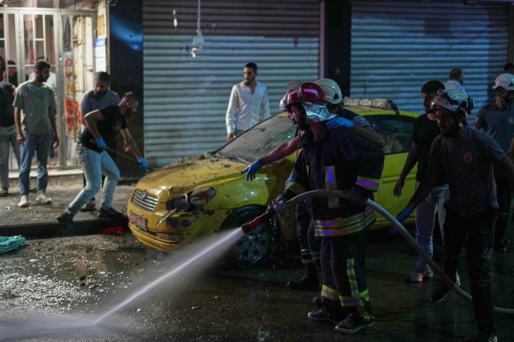 Residents watch as Syrian firefighters clean the site of an explosion in the Jaramana suburb, home to a large Druze population, in Damascus, Syria, Thursday, Aug. 6, 2026. (AP Photo/Omar Albam)