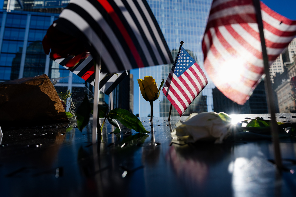 Flags and roses are placed on the edge of the 9/11 Memorial Pools on the 25th anniversary of the September 11 World Trade Center attacks, Friday, Sept. 11, 2026, in New York. (AP Photo/Angelina Katsanis)
