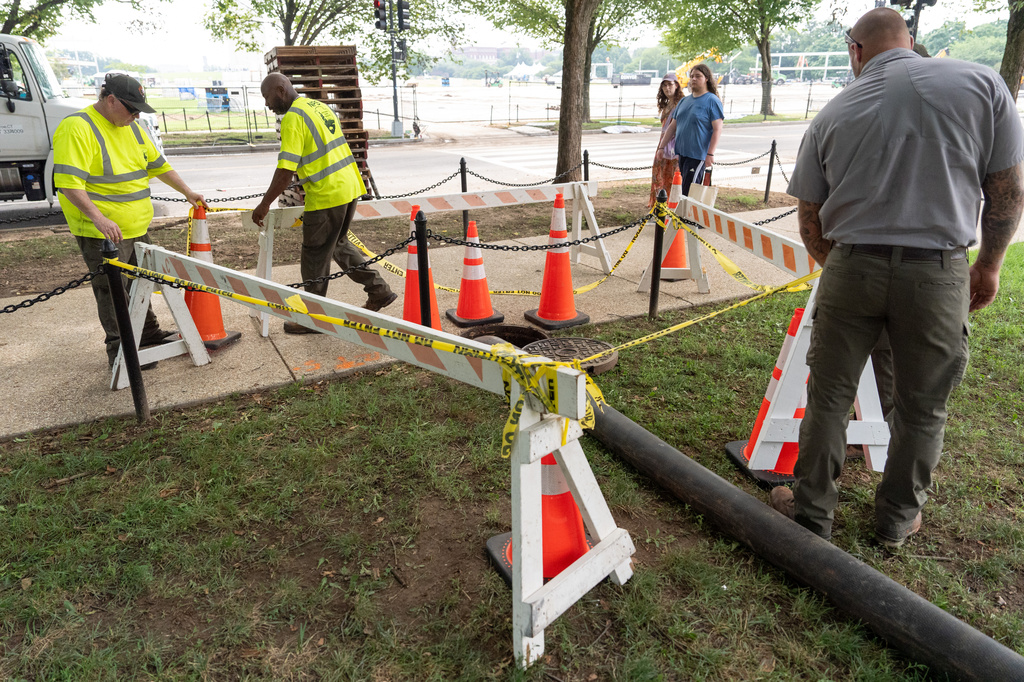 National Park Service workers adjust barricades around a manhole near the World War II Memorial next to the Lincoln Memorial Reflecting Pool, Friday, July 10, 2026, in Washington. (AP Photo/Mark Schiefelbein)