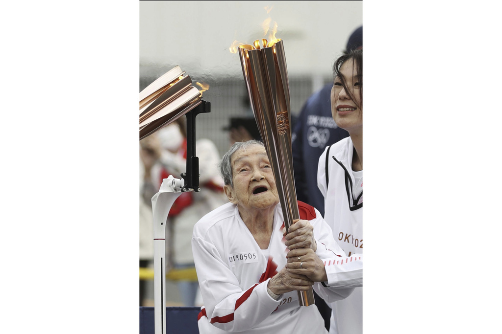 Shigeko Kagawa holds a torch during a torch relay event for the Tokyo Olympics in Yamatokooriyama, Nara prefecture, western Japan, April 12, 2021. (Kyodo News via AP)