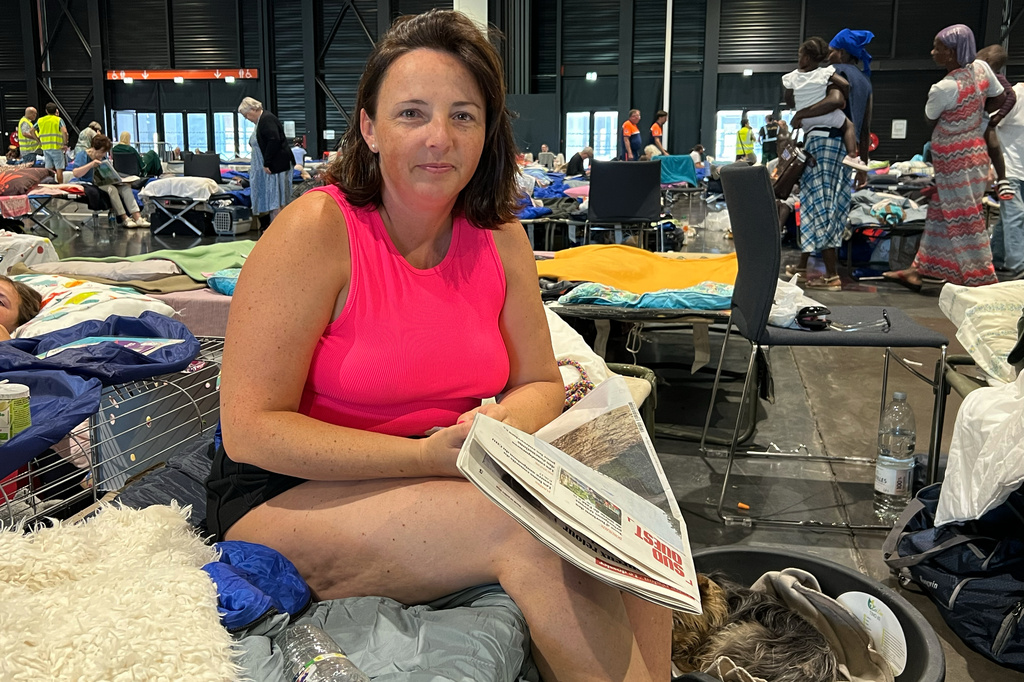 Morgane Bonichot, 40, takes a break from reading a newspaper in an evacuation center in Bordeaux, on Tuesday, July 28, 2026, where she, her daughter, their rabbit and dog are sheltering from wildfires in southwest France. (AP Photo/Eva van Dam)