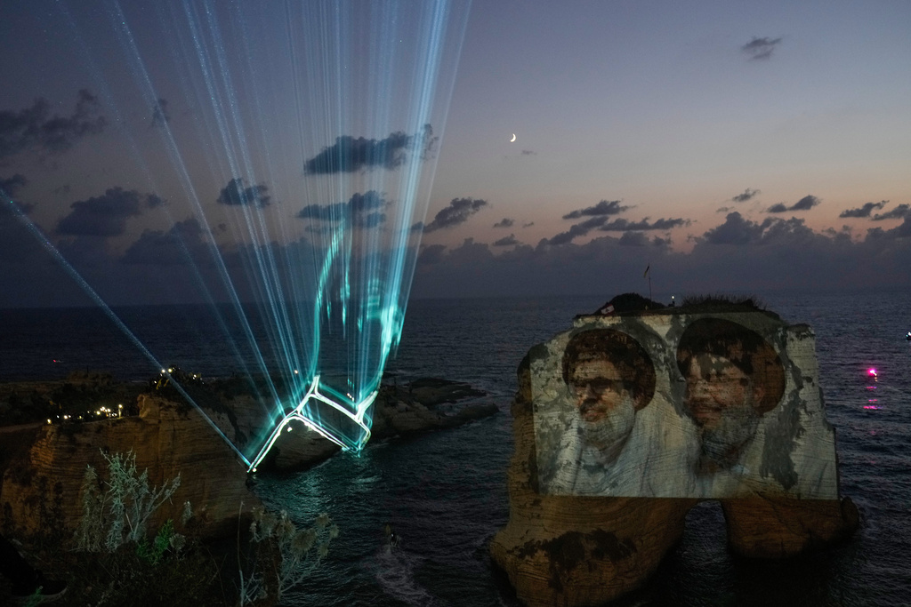 Portraits of former Hezbollah leaders Sayyed Hassan Nasrallah, right, and Hashem Safieddine, are projected onto the landmark Raouche sea rock during an event commemorating the anniversary of their assassination, in Beirut, Lebanon, Thursday, Sept. 25, 2025. (AP Photo/Hussein Malla)