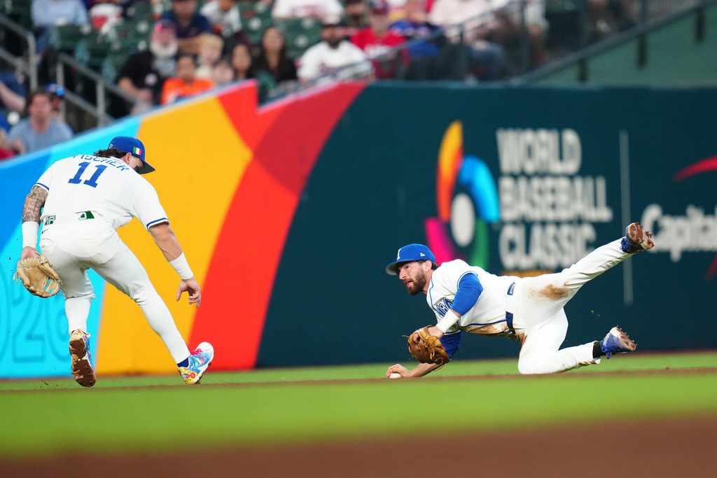 Italy shortstop Thomas Saggese, right, stops a grounder hit for a single by Puerto Rico's Nolan Arenado as Italy's Andrew Fischer (11) watches during the fifth inning of a World Baseball Classic quarterfinal game, Saturday, March 14, 2026, in Houston. (AP Photo/Karen Warren)