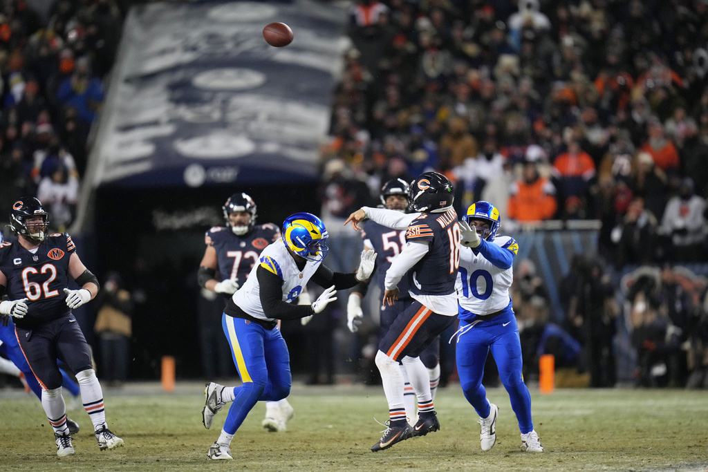 Chicago Bears quarterback Caleb Williams (18) throws a touchdown pass to tight end Cole Kmet, not visible, as Los Angeles Rams linebacker Josaiah Stewart (10) and linebacker Jared Verse (8) apply pressure during the second half of an NFL football divisional playoff game Sunday, Jan. 18, 2026, in Chicago. (AP Photo/Jeff Roberson)