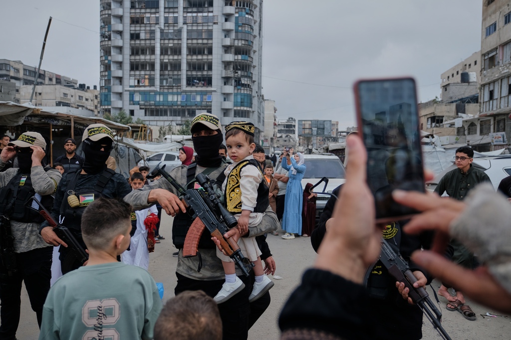 Palestinians take photos with Islamic Jihad militants as they gather for Eid al-Adha prayers in Gaza City Wednesday, May 27, 2026. (AP Photo/Jehad Alshrafi)