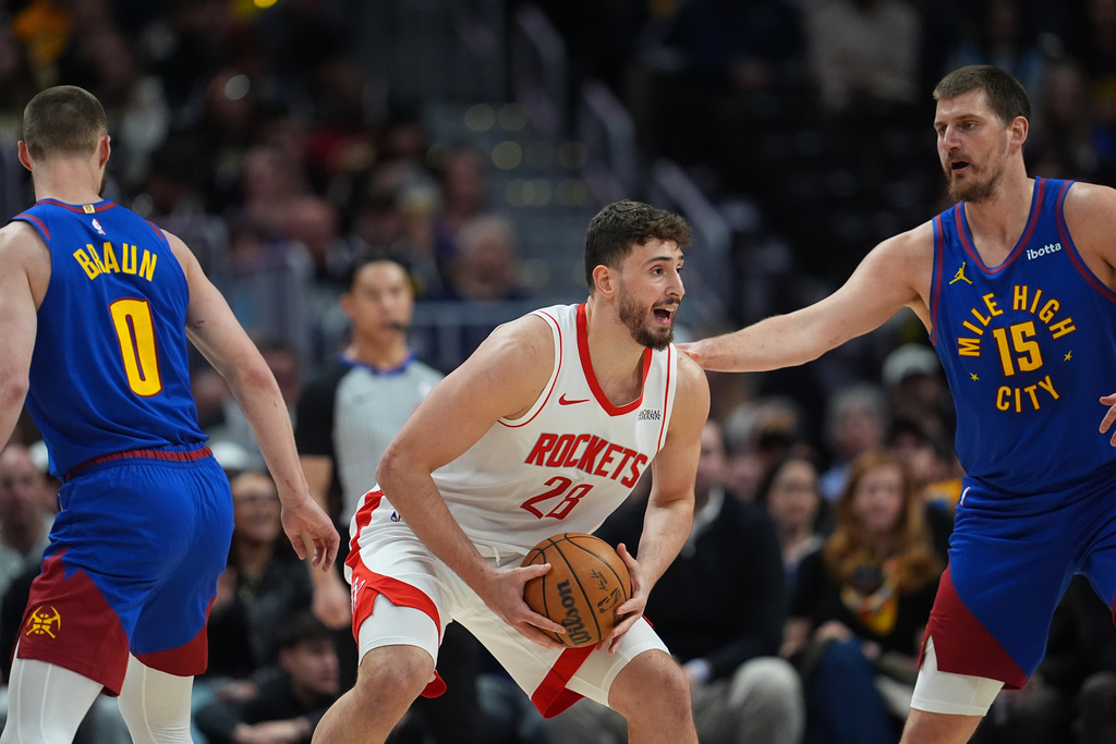 Houston Rockets center Alperen Sengun, center, looks to pass the ball as Denver Nuggets guard Christian Braun, left, and center Nikola Jokic defend in the first half of an NBA basketball game Wednesday, March 11, 2026, in Denver. (AP Photo/David Zalubowski)