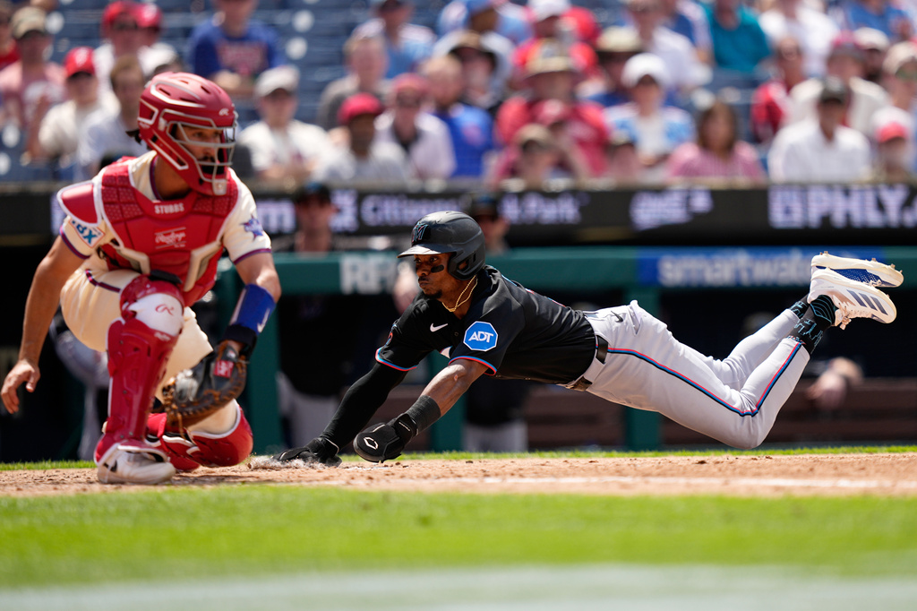 Miami Marlins' Esteury Ruiz, right, scores past Philadelphia Phillies catcher Garrett Stubbs on a sacrifice fly by Otto Lopez during the sixth inning of a baseball game Wednesday, June 17, 2026, in Philadelphia. (AP Photo/Matt Slocum)