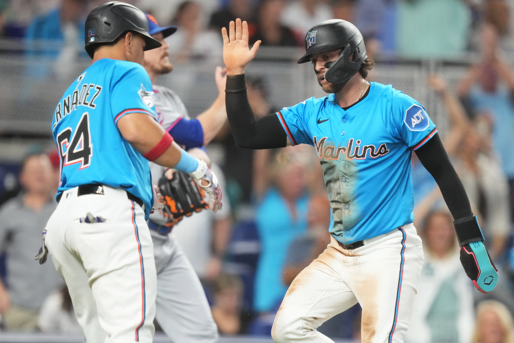 Miami Marlins' Connor Norby, right, is met by Heriberto Hernandez (64) after scoring on a double hit by Eric Wagaman during the fourth inning of a baseball game against the New York Mets1, Sunday, Sept. 28, 2025, in Miami. (AP Photo/Lynne Sladky)