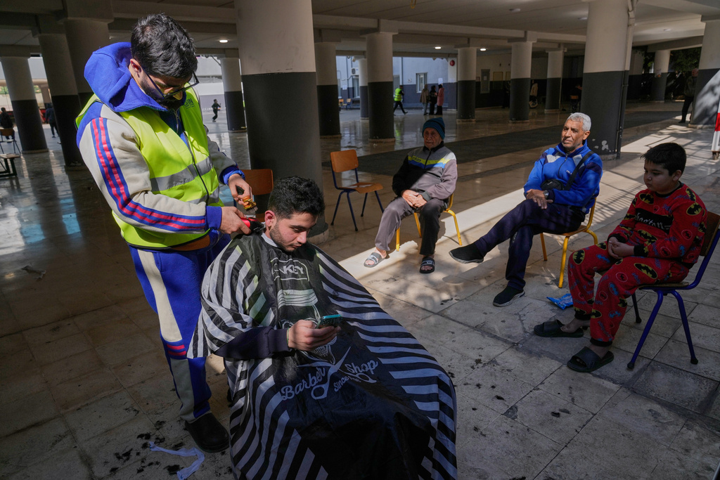 A displaced man who fled Israeli strikes in southern Lebanon receives a haircut in the playground of a school turned into a shelter in Beirut, Lebanon, Tuesday, March 10, 2026. (AP Photo/Hussein Malla)