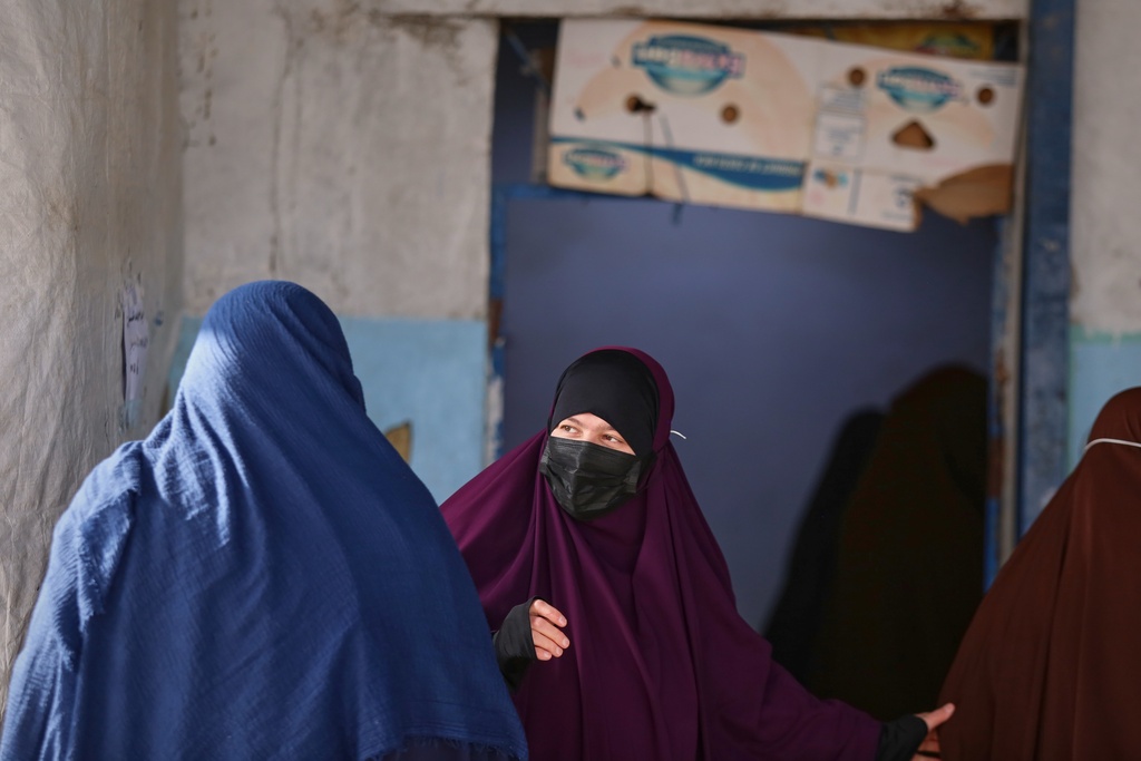 Women wait to enter a building supplying food and other goods at Roj camp, one of the detention facilities holding thousands of Islamic State group members and their families, in the al-Malikiyah area of northeastern Syria, Thursday, Jan. 29, 2026. (AP Photo/Baderkhan Ahmad)