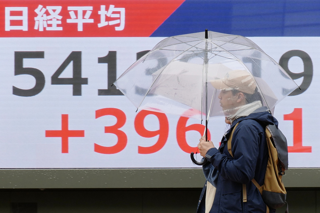Persons walk in front of an electronic stock board showing Japan's Nikkei index at a securities firm Thursday, April 2, 2026, in Tokyo. (AP Photo/Eugene Hoshiko)
