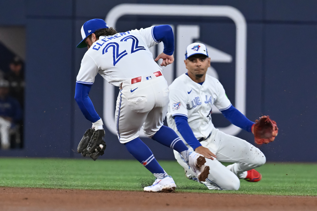 Toronto Blue Jays' Ernie Clement (22) fields a ground ball off the bat of Colorado Rockies infielder Kyle Karros in front of teammate Andres Gimenez during fourth inning interleague baseball action in Toronto on Monday, March 30, 2026.