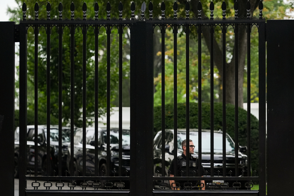 A U.S. Secret Service agent watches through a fence as President Donald Trump departs the White House en route to Trump National Golf Club, Sunday, Aug. 30, 2026, in Washington. (AP Photo/Julia Demaree Nikhinson)