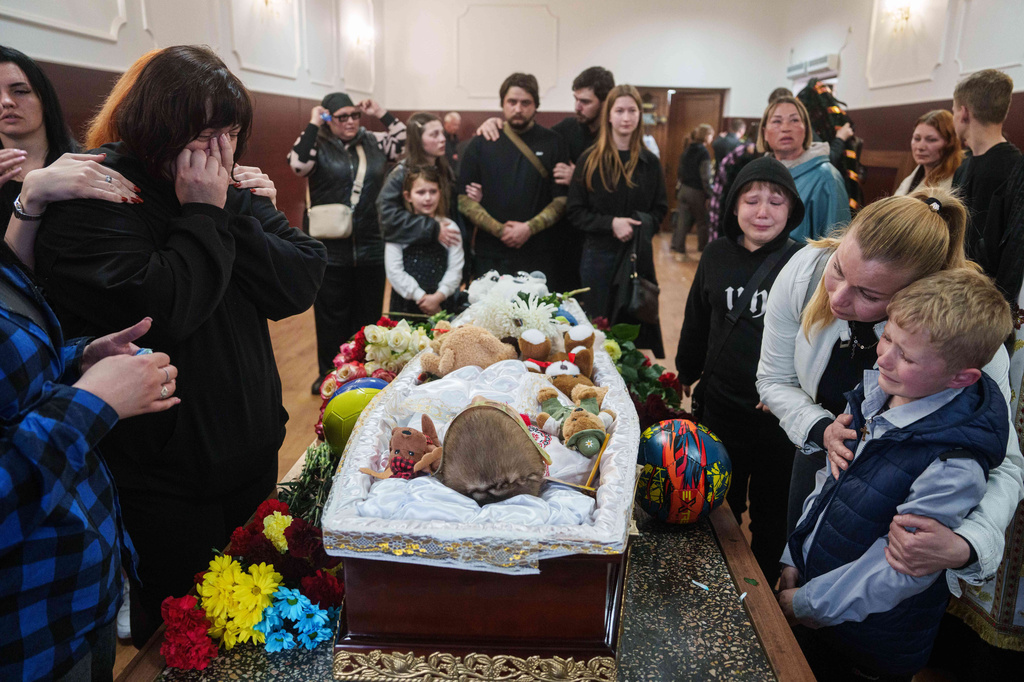 People cry around the coffin that contains the remains of 8-year-old Bohdan Serhiiev killed in a Russian drone attack, during a farewell ceremony in Cherkasy, Ukraine, Thursday, April 16, 2026. (AP Photo/Evgeniy Maloletka)
