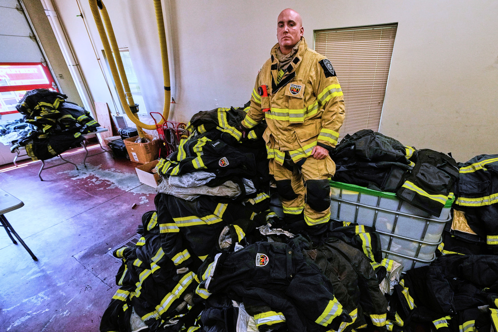 Firefighter Christopher Harrington stands next to the station's old turnout gear, while wearing recently issued non-PFAS turnout gear, at Fire Station 4 on July 3, 2025, in East Providence, R.I. (AP Photo/Charles Krupa)