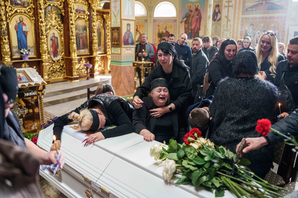 A mother surrounded by family cries sitting by the coffin of her son Illia Honcharenko, 14, killed by a Russian rocket strike on a residential house on Sept. 30, during their funeral, in Vyshhorod, Kyiv region, Ukraine, Friday, Oct. 2, 2026. (AP Photo/Evgeniy Maloletka)