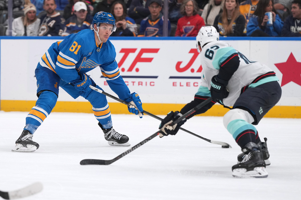 St. Louis Blues' Dylan Holloway (81) handles the puck as Seattle Kraken's Brandon Montour, right, defends during the second period of an NHL hockey game Saturday, Nov. 8, 2025, in St. Louis. (AP Photo/Jeff Roberson)