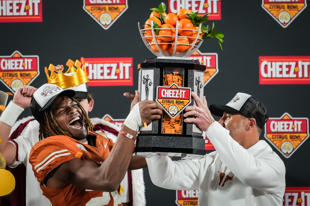 Texas Longhorns linebacker Ty'Anthony Smith (26) lifts the trophy with head coach Steve Sarkisianas of the Longhorns celebrate after winning the Citrus Bowl 41-27 against the Michigan Wolverines at Camping World Stadium in Orlando, Fla, Dec. 31, 2025. (Sara Diggins/Austin American-Statesman via AP)
