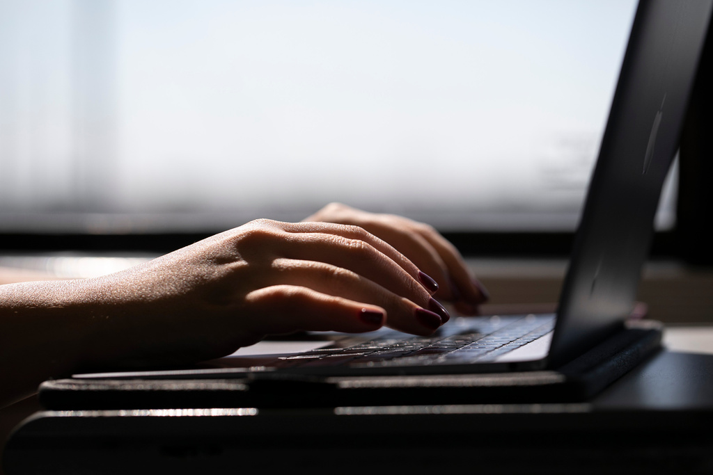 FILE - This May 18, 2021, photo shows a woman typing on a laptop on a train in New Jersey. (AP Photo/Jenny Kane, File)