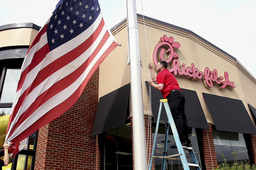 Chick-fil-A employees lower a U.S. flag outside their restaurant on Thursday, Sept. 13, 2018. (Alan Campbell/Rocky Mount Telegram via AP)
