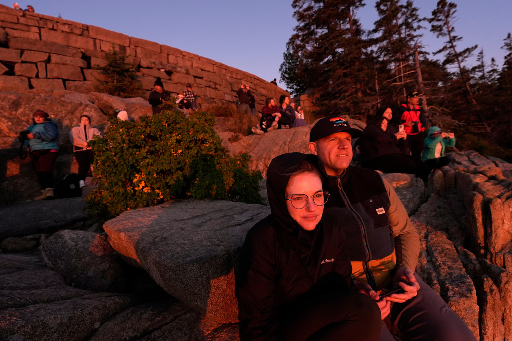 Kaitlin and Kurt Wilhelm, of Sandusky, Ohio, foreground, and others gather on the rocky coast to watch the sunrise, Wednesday, Oct. 1, 2025, in Acadia National Park, Maine. (AP Photo/Robert F. Bukaty)