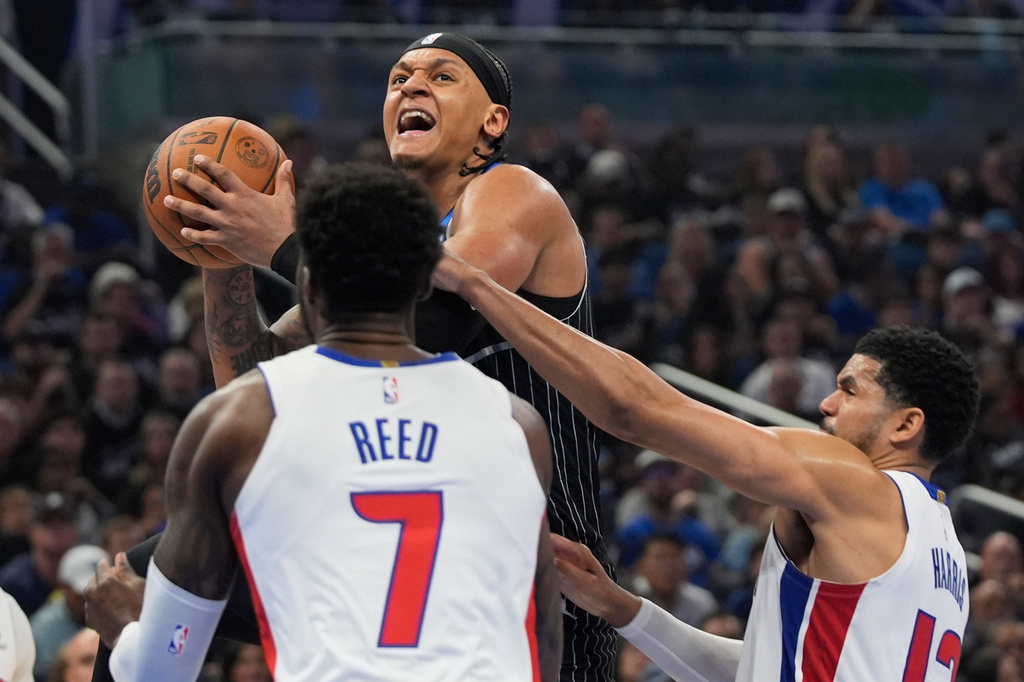 Orlando Magic forward Paolo Banchero, center, goes up for a shot over Detroit Pistons forward Paul Reed (7) and forward Tobias Harris, right, during the second half in Game 3 of a first-round NBA basketball playoff series, Saturday, April 25, 2026, in Orlando, Fla. (AP Photo/John Raoux)