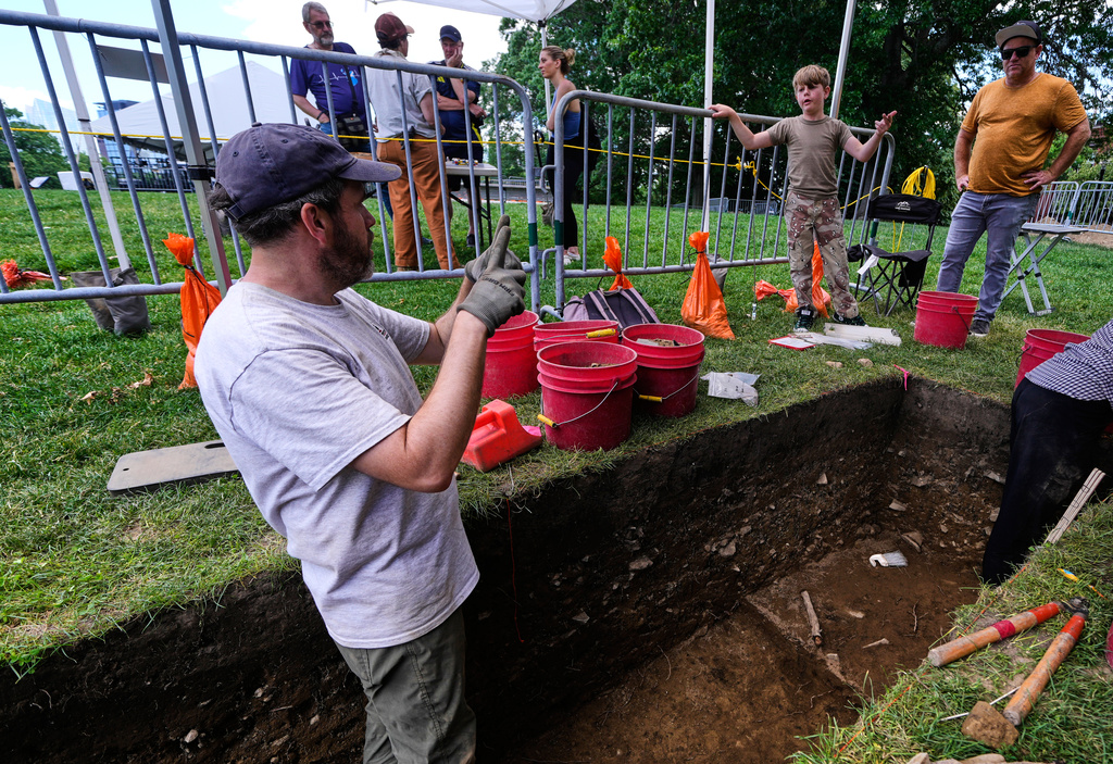 Joe Bagley, the City of Boston Archeologist, left, chats with visitor Owen MacDonald, of Los Angeles, who was visiting Boston with his father John, during an archaeological dig at the site of the Battle of Bunker Hill, Monday, June 15, 2026, in Boston. (AP Photo/Charles Krupa)