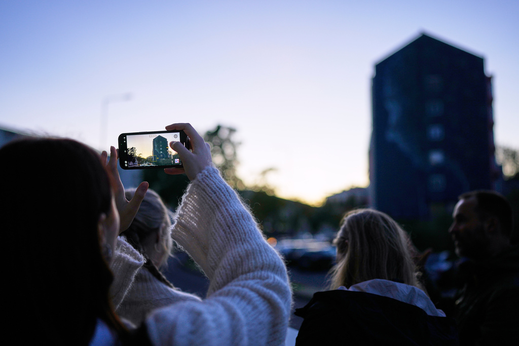 A university student from Finland on a tour takes pictures of a mural by artist Jacqueline de Montaigne, inspired by the United Nations Sustainable Development Goal 15, Life on Land, at the housing project Zambujal in Amadora, on the outskirts of the Portuguese capital Lisbon, Tuesday, Nov. 18, 2025. (AP Photo/Armando Franca)