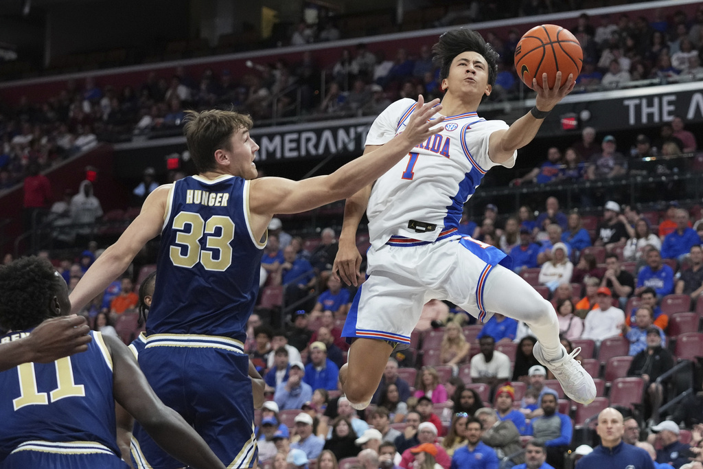 Florida guard Xaivian Lee (1) goes to the basket as George Washington forward Luke Hunger (33) defends during the first half of an NCAA college basketball game at the Orange Bowl Basketball Classic, Saturday, Dec. 13, 2025, in Sunrise, Fla. (AP Photo/Lynne Sladky)