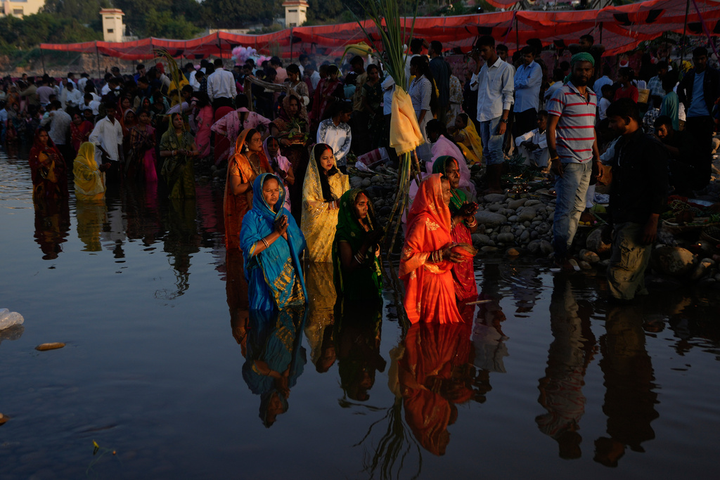 Hindu devotees perform rituals at sunset on the banks of the Tawi River during Chhath Puja festival in Jammu, India, Monday, Oct. 27, 2025.(AP Photo/Channi Anand)