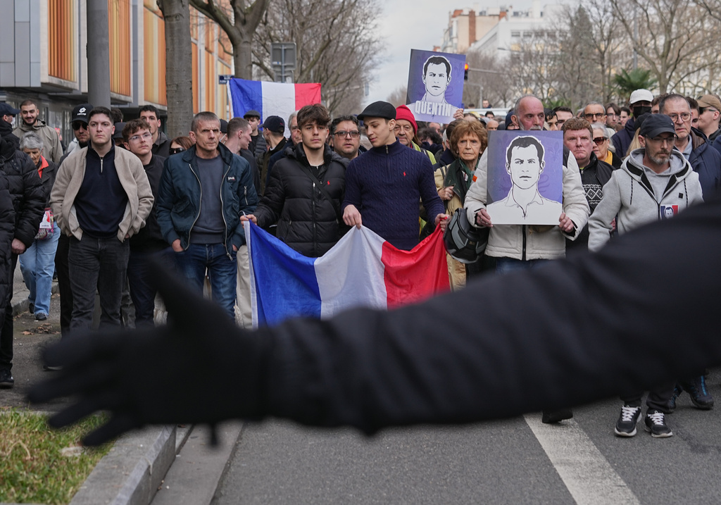 People take part in a march with French national flags and portraits of the killed student in Lyon, France, Saturday, Feb. 21, 2026, to pay tribute to Quentin Deranque, a 23-year-old nationalist activist who died from a beating after a clash between far-left and far-right supporters. (AP Photo/Laurent Cipriani)