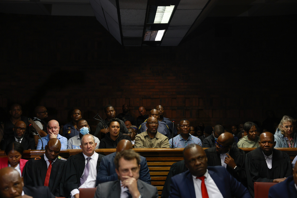 An alleged crime boss Vusimuzi "Cat" Matlala, far left of the middle row, with some of the 12 senior police officers have been arrested, appearing at the magistrate court in Pretoria, South Africa, Wednesday, March 25, 2026, on fraud and corruption charges. (AP Photo)